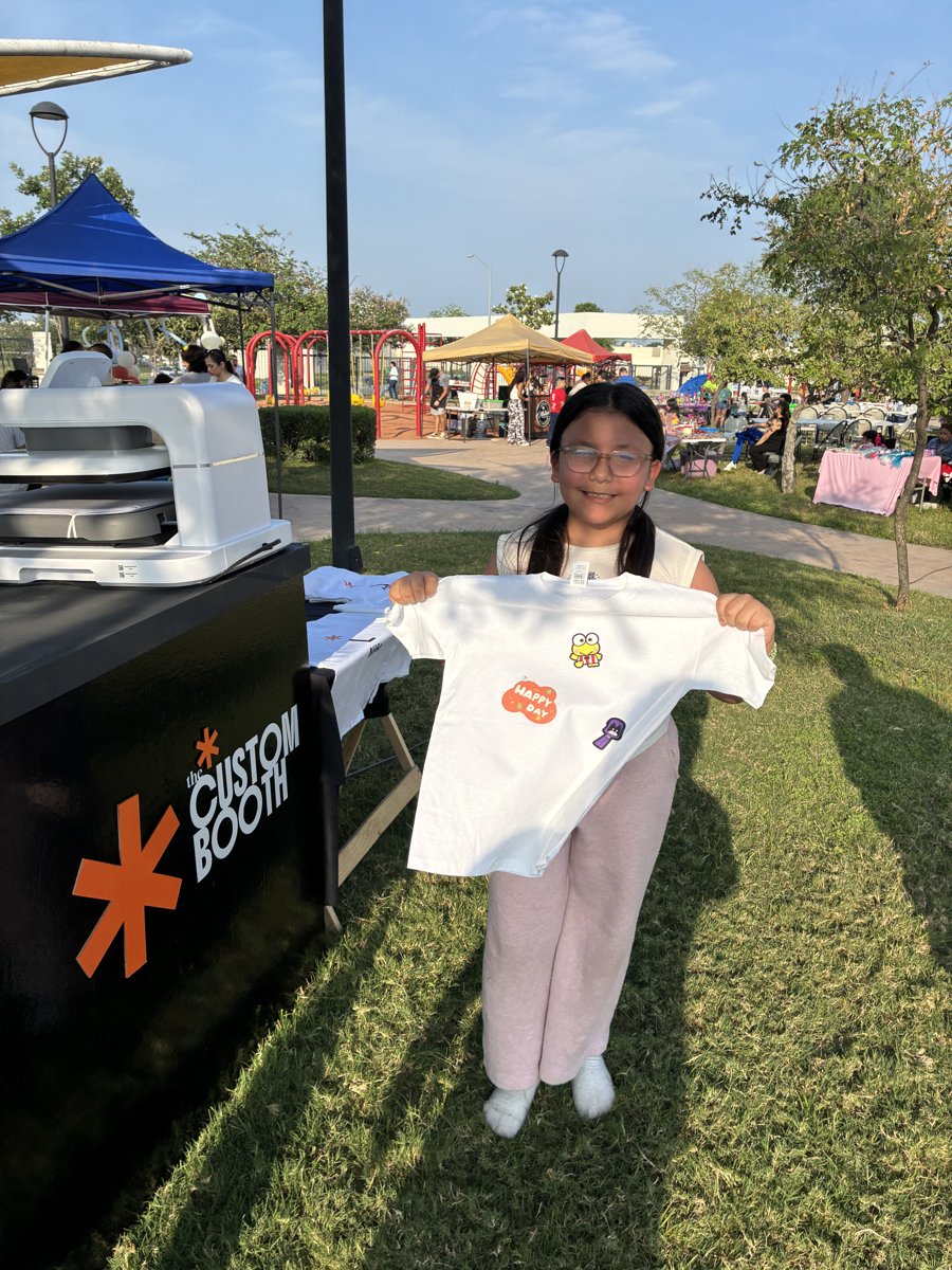 Niña mostrando su playera personalizada terminada junto al booth